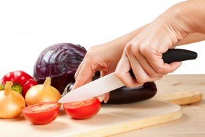 ceramic knife with vegetables on cutting board